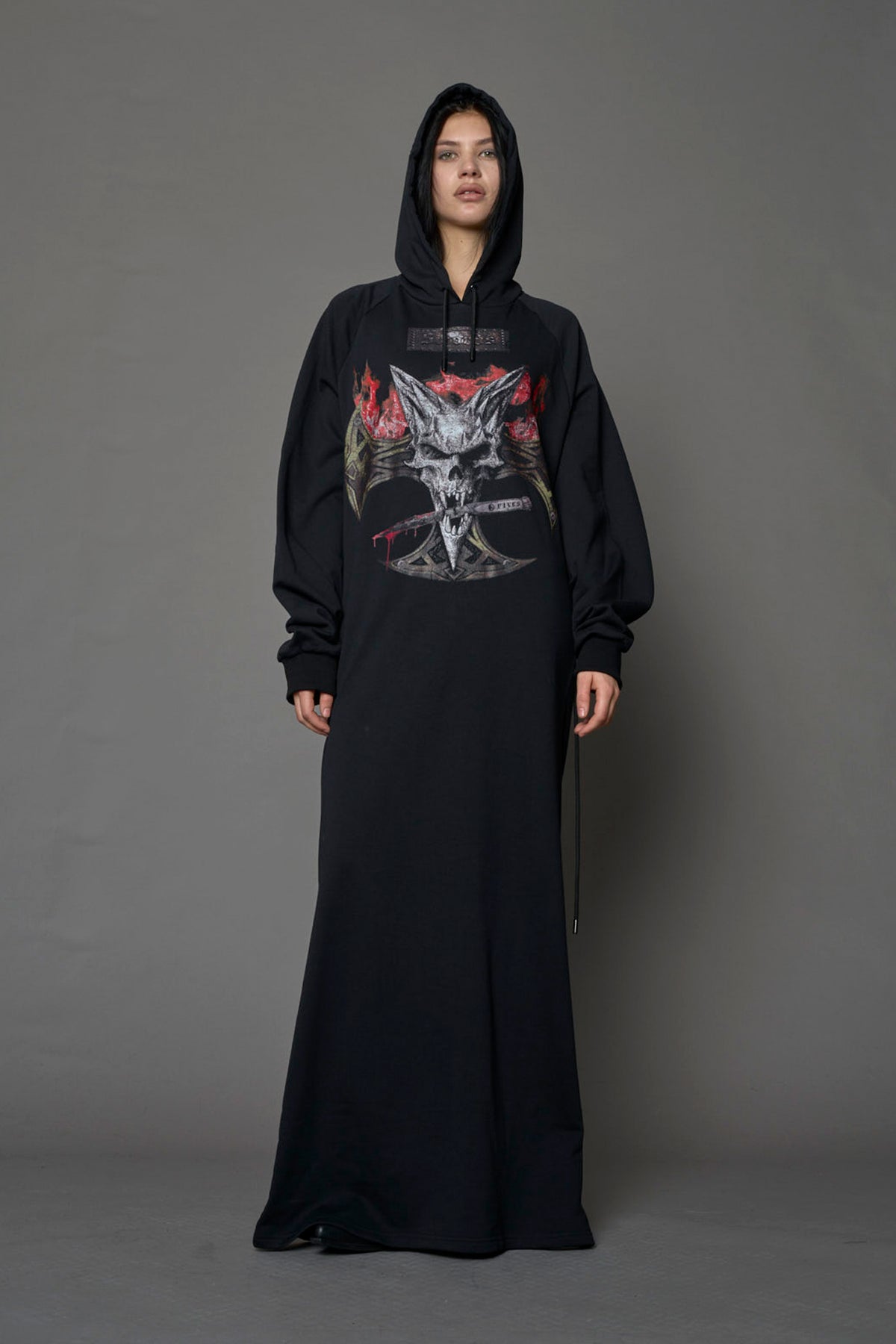 Model wearing a long black hoodie dress with a goth-inspired print detail