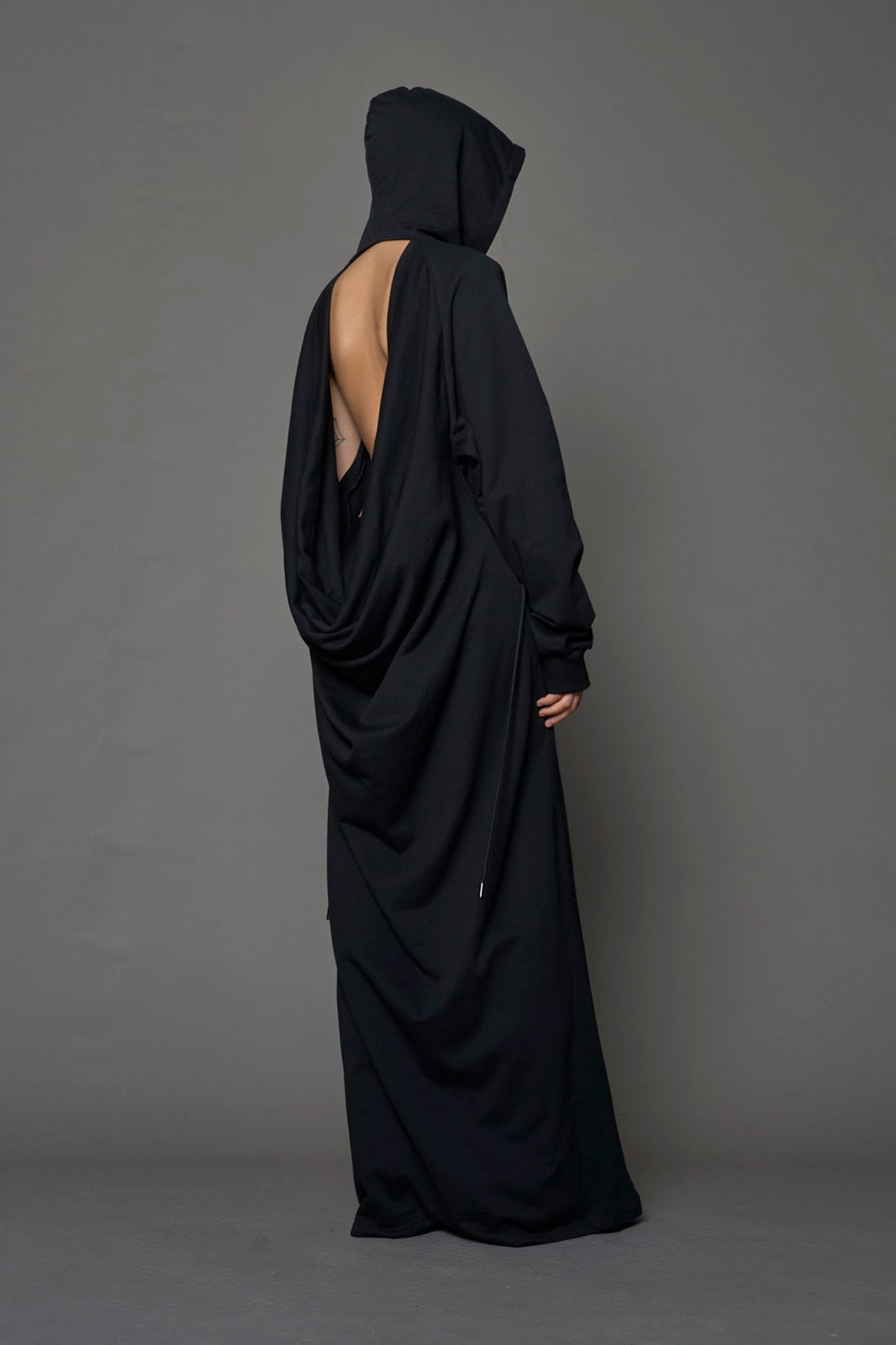 Model wearing a long black hoodie dress with a goth-inspired print detail