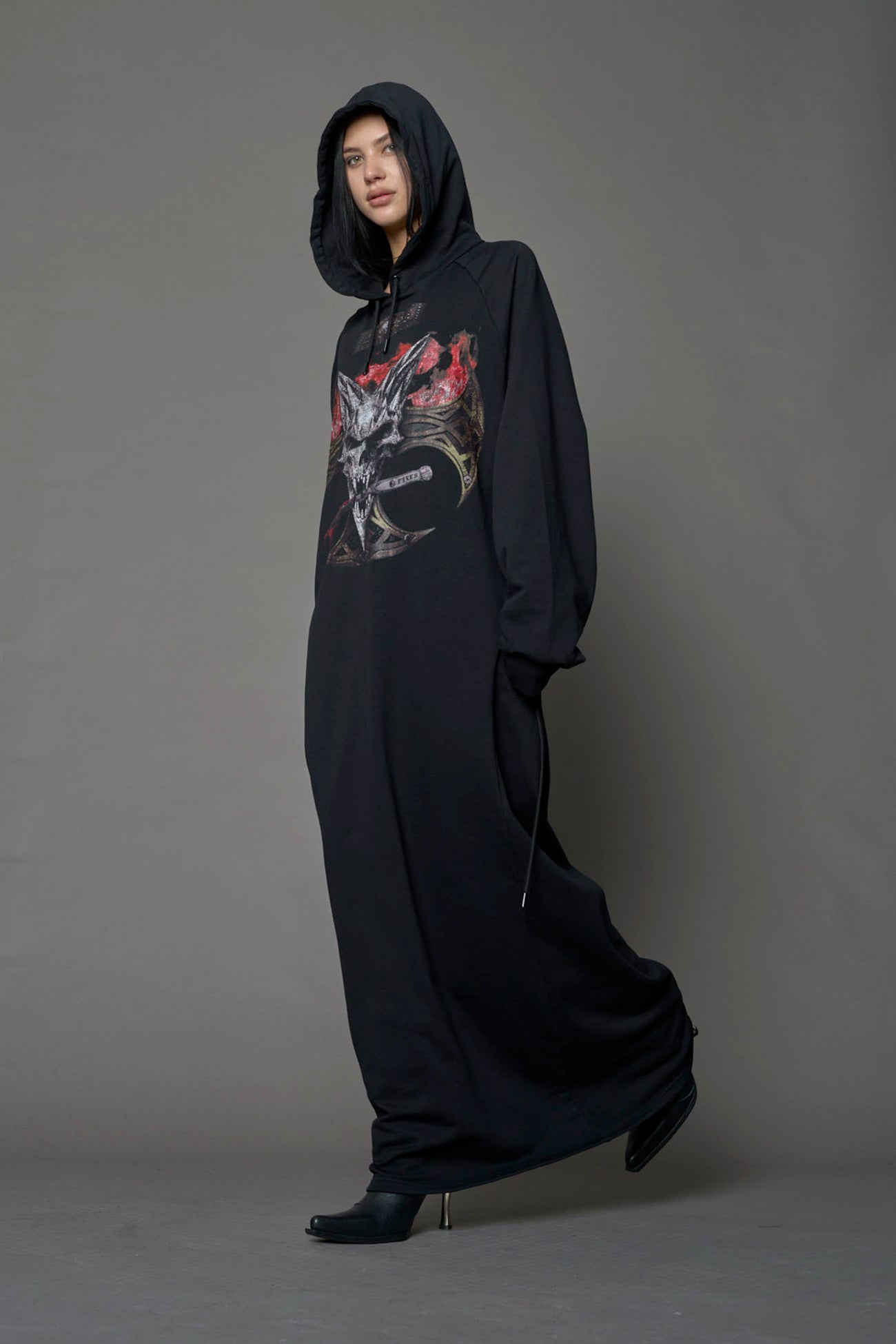 Model wearing a long black hoodie dress with a goth-inspired print detail
