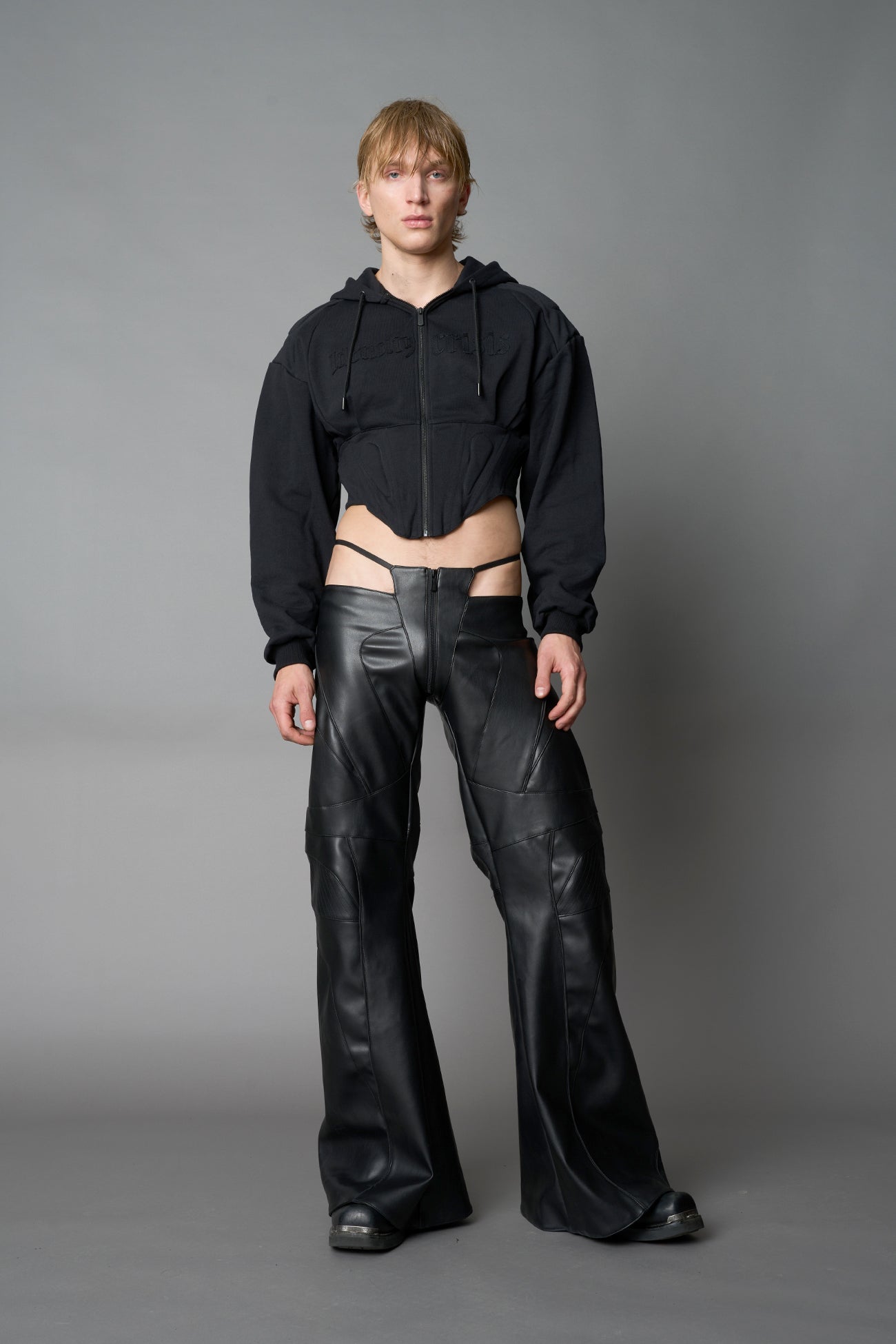 model in a black cropped hoodie featuring structured corset-style paneling  embroidered across the chest in tonal black