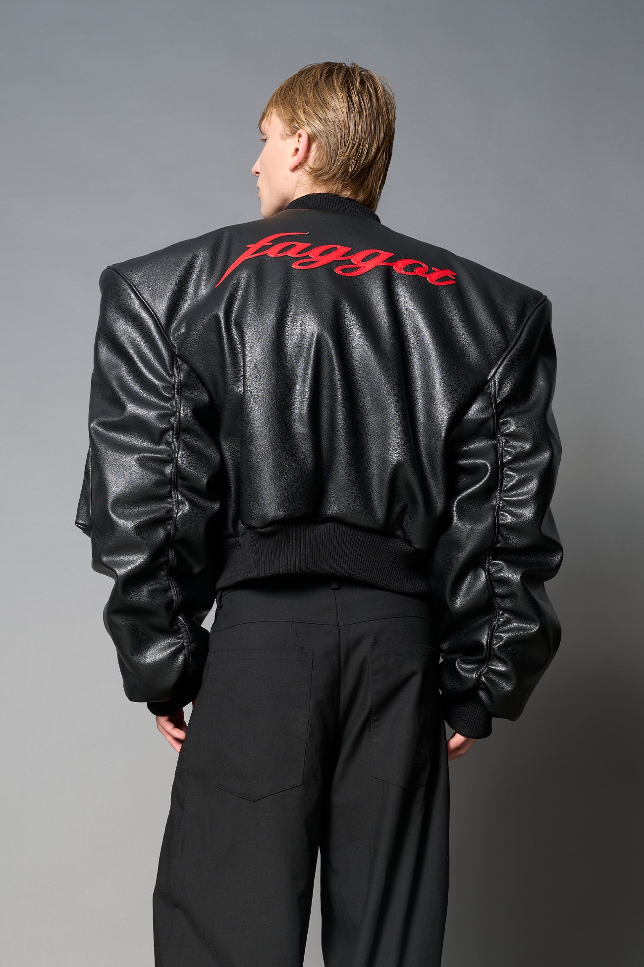 model wears red oversize cropped vegan leather bomber with exaggerated shoulderpads and ruching on sleeves.