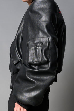 model wears red oversize cropped vegan leather bomber with exaggerated shoulderpads and ruching on sleeves.