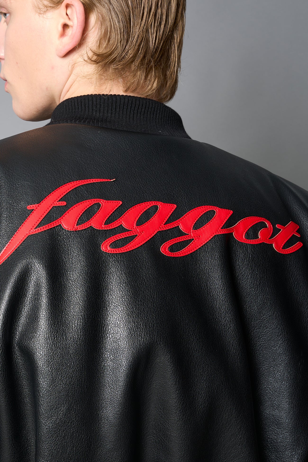 model wears red oversize cropped vegan leather bomber with exaggerated shoulderpads and ruching on sleeves.