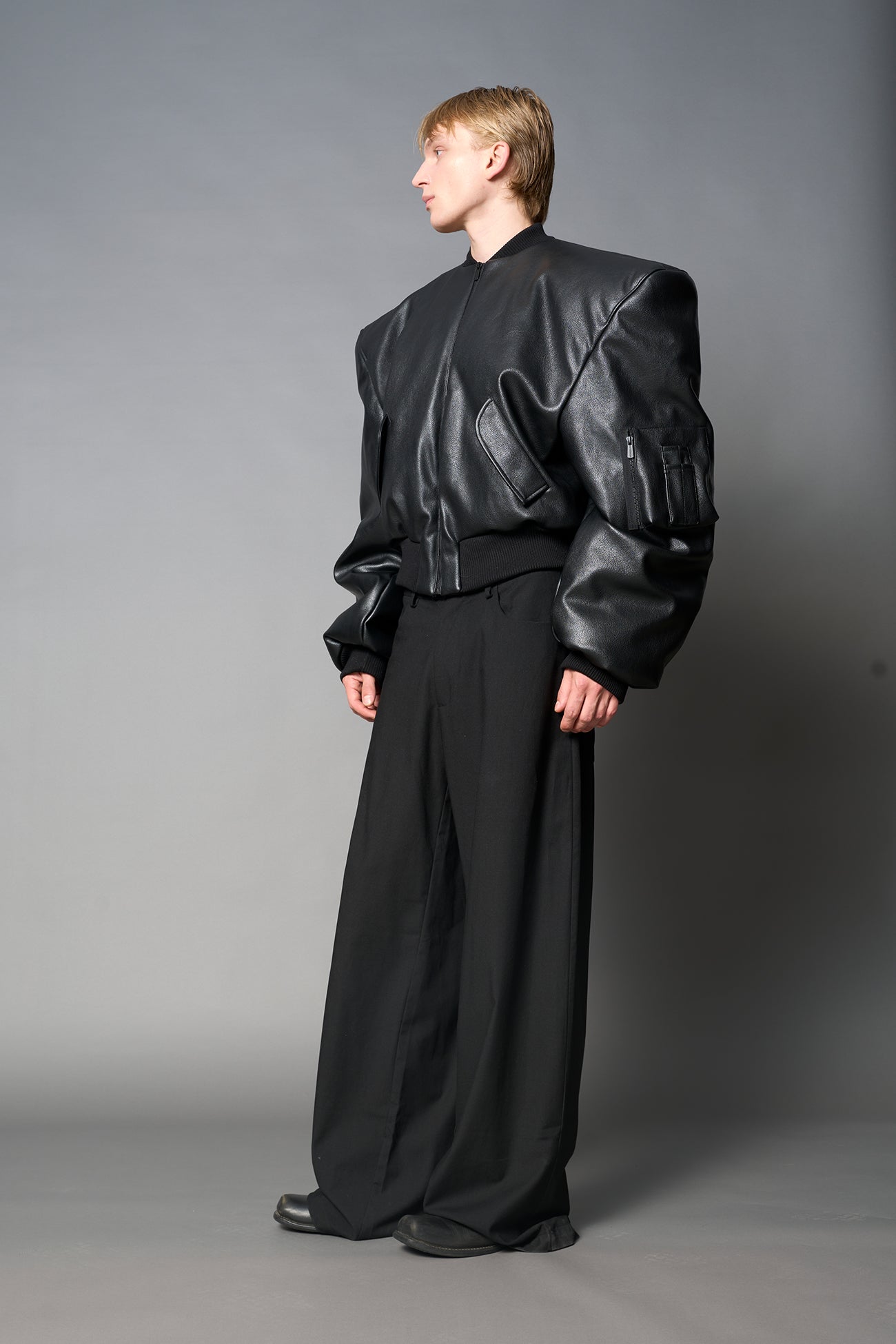 model wears red oversize cropped vegan leather bomber with exaggerated shoulderpads and ruching on sleeves.