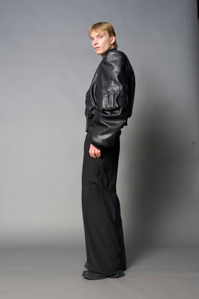 model wears red oversize cropped vegan leather bomber with exaggerated shoulderpads and ruching on sleeves.