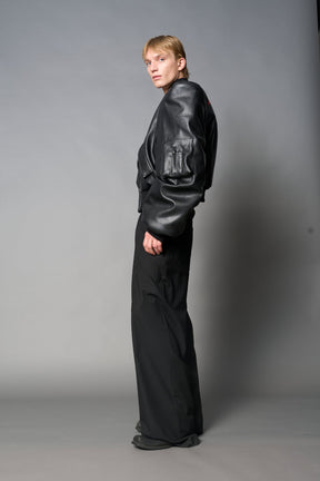 model wears red oversize cropped vegan leather bomber with exaggerated shoulderpads and ruching on sleeves.