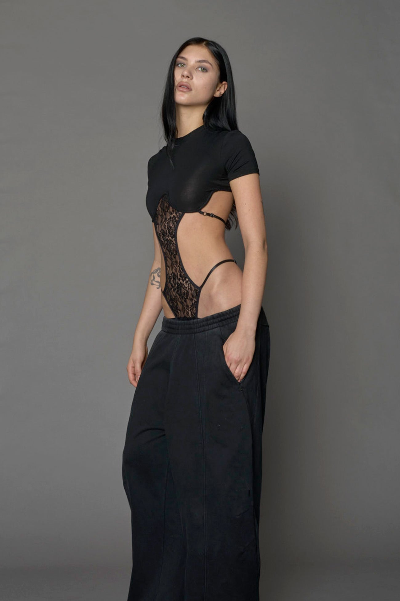 Model wearing a black form fitted T-Shirt bodysuit with lace details