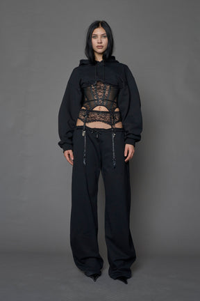 female model wearing a black low waist jogger with a lace suspender belt 