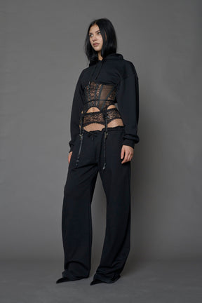female model wearing a black low waist jogger with a lace suspender belt 
