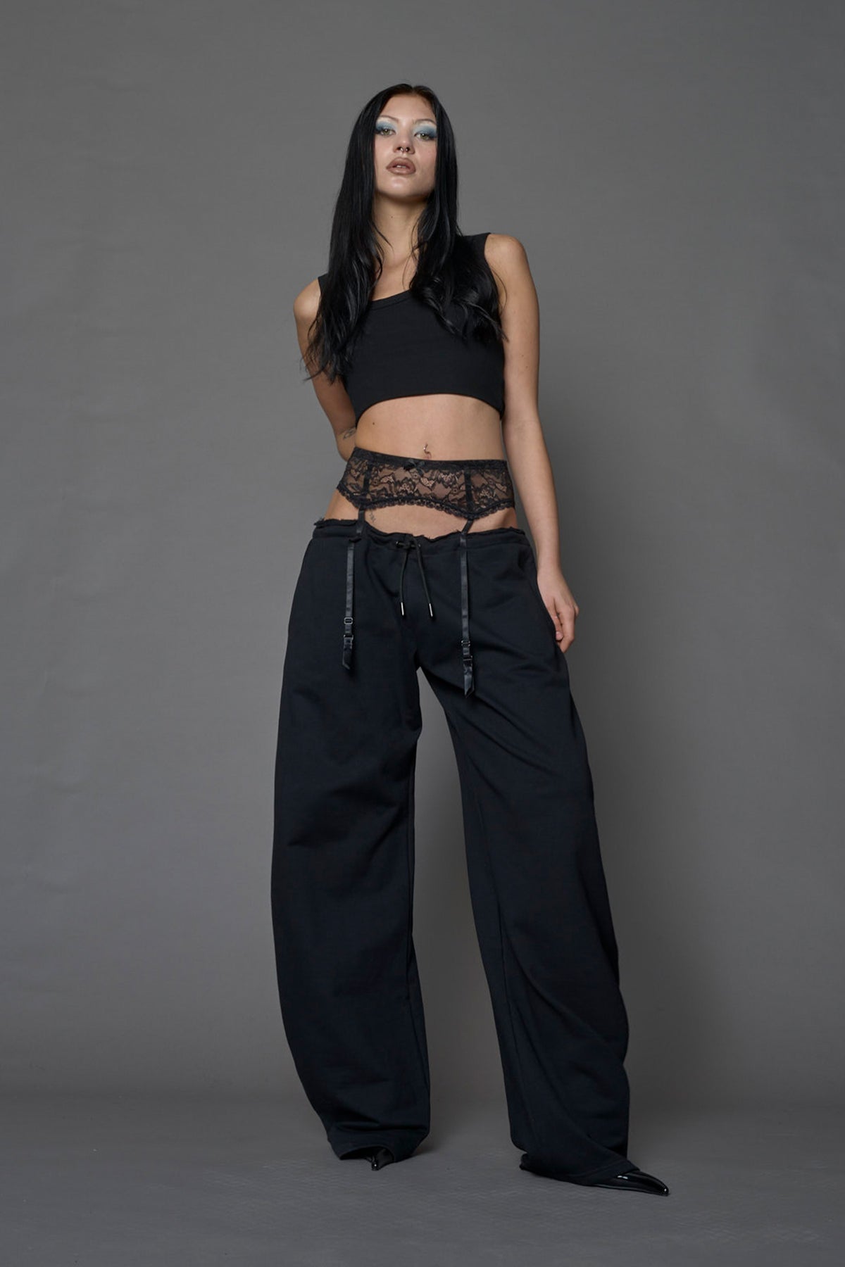 female model wearing a black low waist jogger with a lace suspender belt 