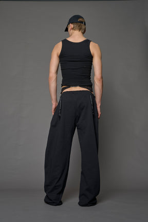 male model wearing a black low waist jogger with a lace suspender belt 