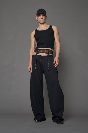 male model wearing a black low waist jogger with a lace suspender belt 
