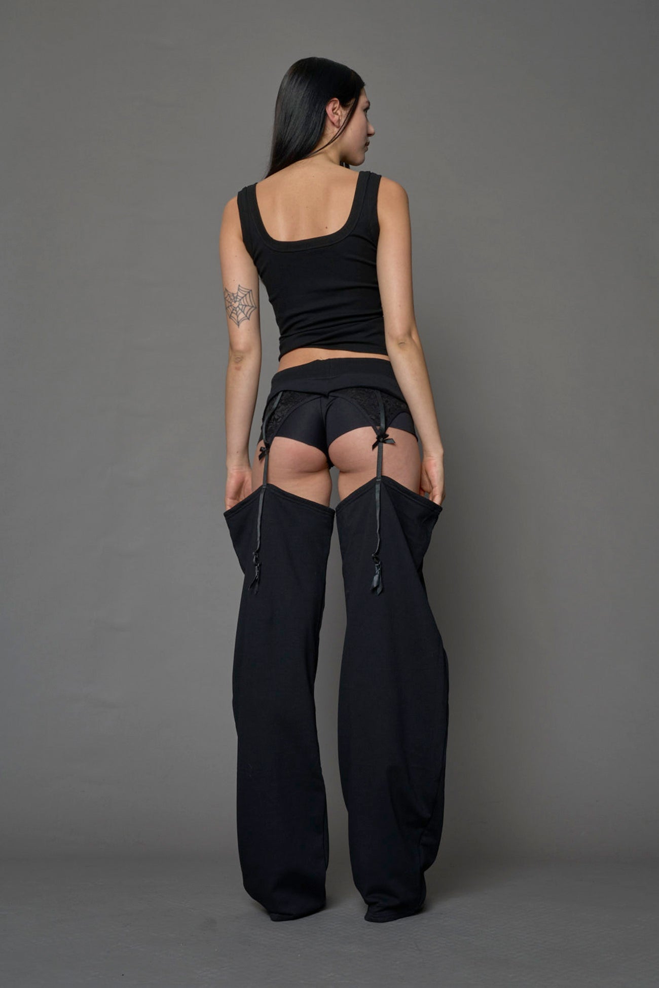 model wearing black jogger-inspired chaps with a lace suspender belt 