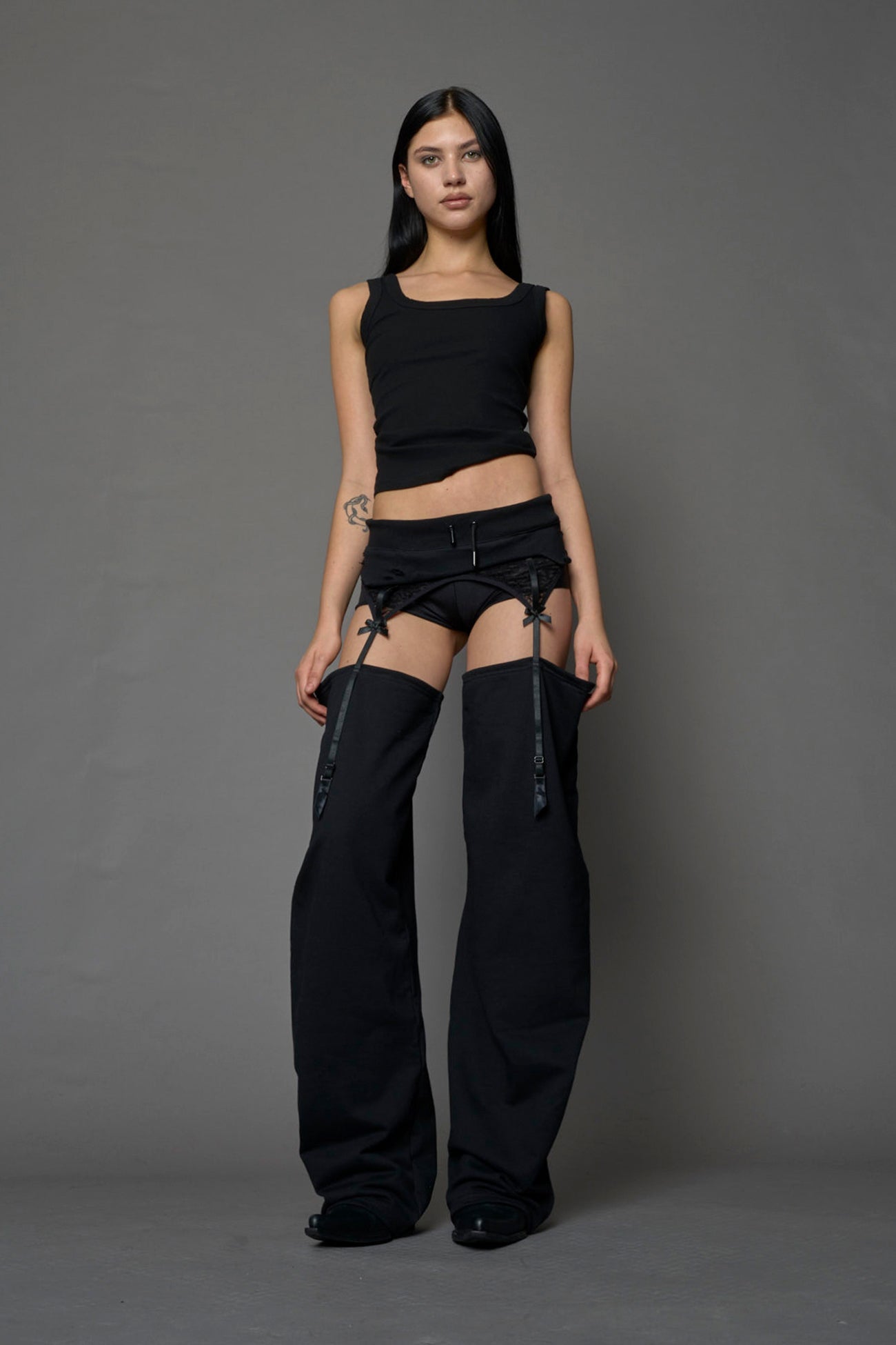 model wearing black jogger-inspired chaps with a lace suspender belt 