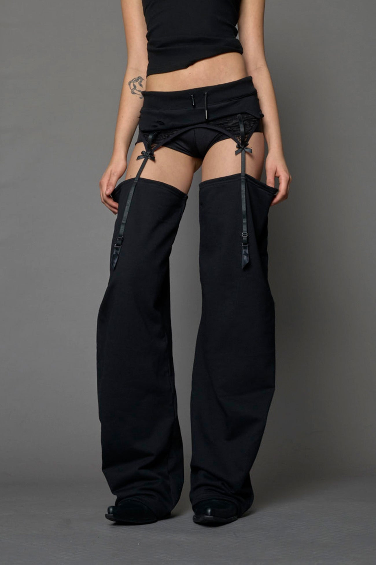 model wearing black jogger-inspired chaps with a lace suspender belt 