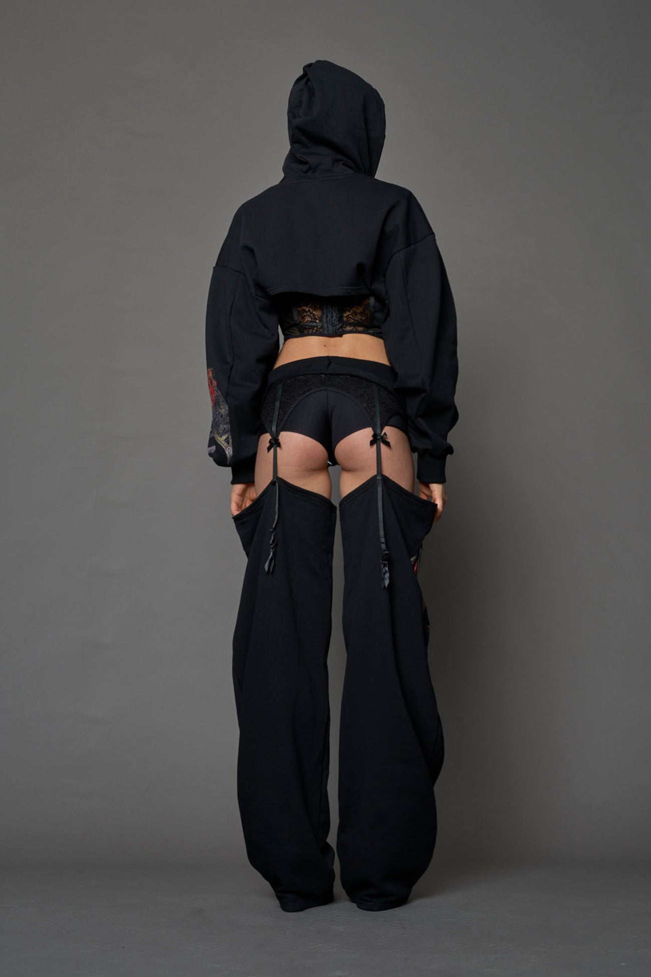 model wearing black jogger-inspired chaps with a lace suspender belt 