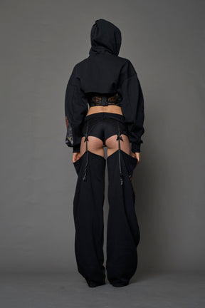 model wearing black jogger-inspired chaps with a lace suspender belt 