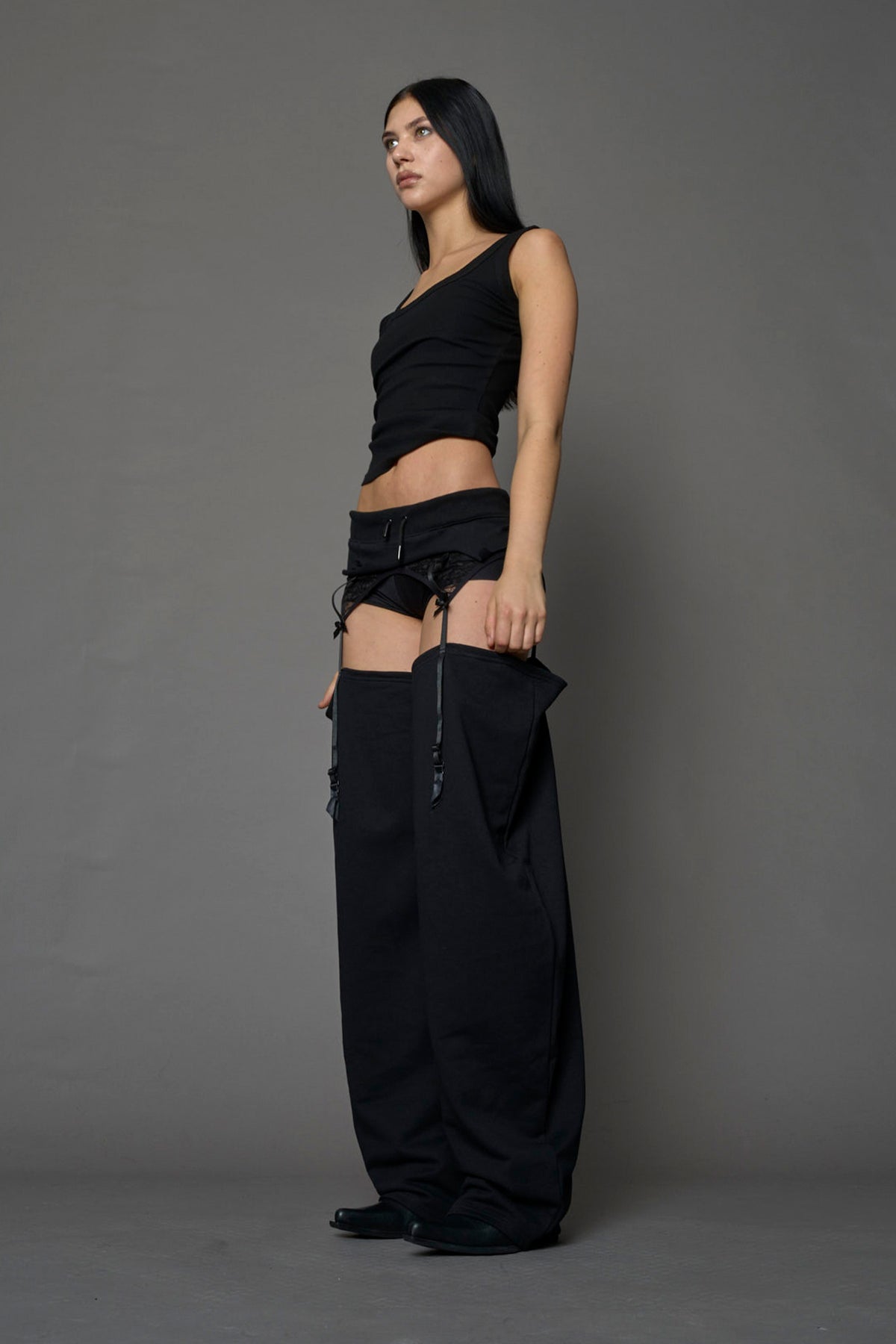model wearing black jogger-inspired chaps with a lace suspender belt 