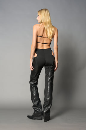 Black cut-out flare pants with graphic details, vegan leather panels, and low-rise waist – edgy motocross-inspired trousers for men’s streetwear or festival looks.