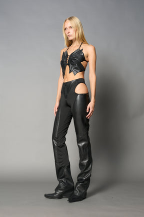 model wears black vegan leather butterfly crop top with lace-up front, halter straps, and mesh accents – edgy Y2K-inspired statement piece for festivals or streetwear.