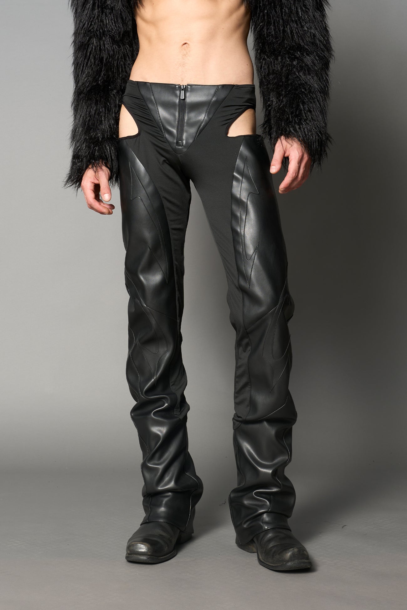 Black cut-out flare pants with graphic details, vegan leather panels, and low-rise waist – edgy motocross-inspired trousers for men’s streetwear or festival looks.