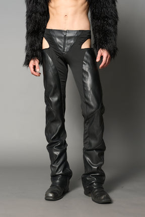 Black cut-out flare pants with graphic details, vegan leather panels, and low-rise waist – edgy motocross-inspired trousers for men’s streetwear or festival looks.