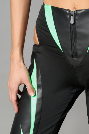Green cut-out flare pants with graphic details, vegan leather panels, and low-rise waist – edgy motocross-inspired trousers for men’s streetwear or festival looks.