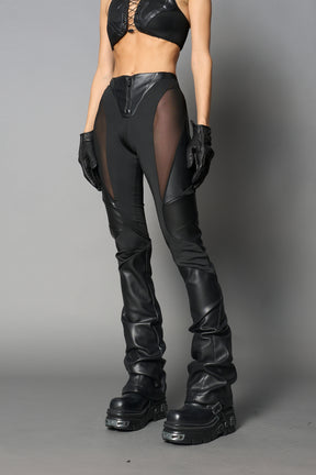 Model wearing high-waisted black vegan leather pants with mesh cutouts, moto-inspired paneling, and flared stacked legs – edgy streetwear trousers styled with chunky platform boots