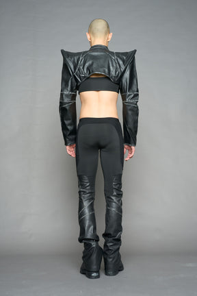 Model wearing high-waisted black washed vegan leather pants with mesh cutouts, moto-inspired paneling, and flared stacked legs – edgy streetwear trousers styled with chunky platform boots