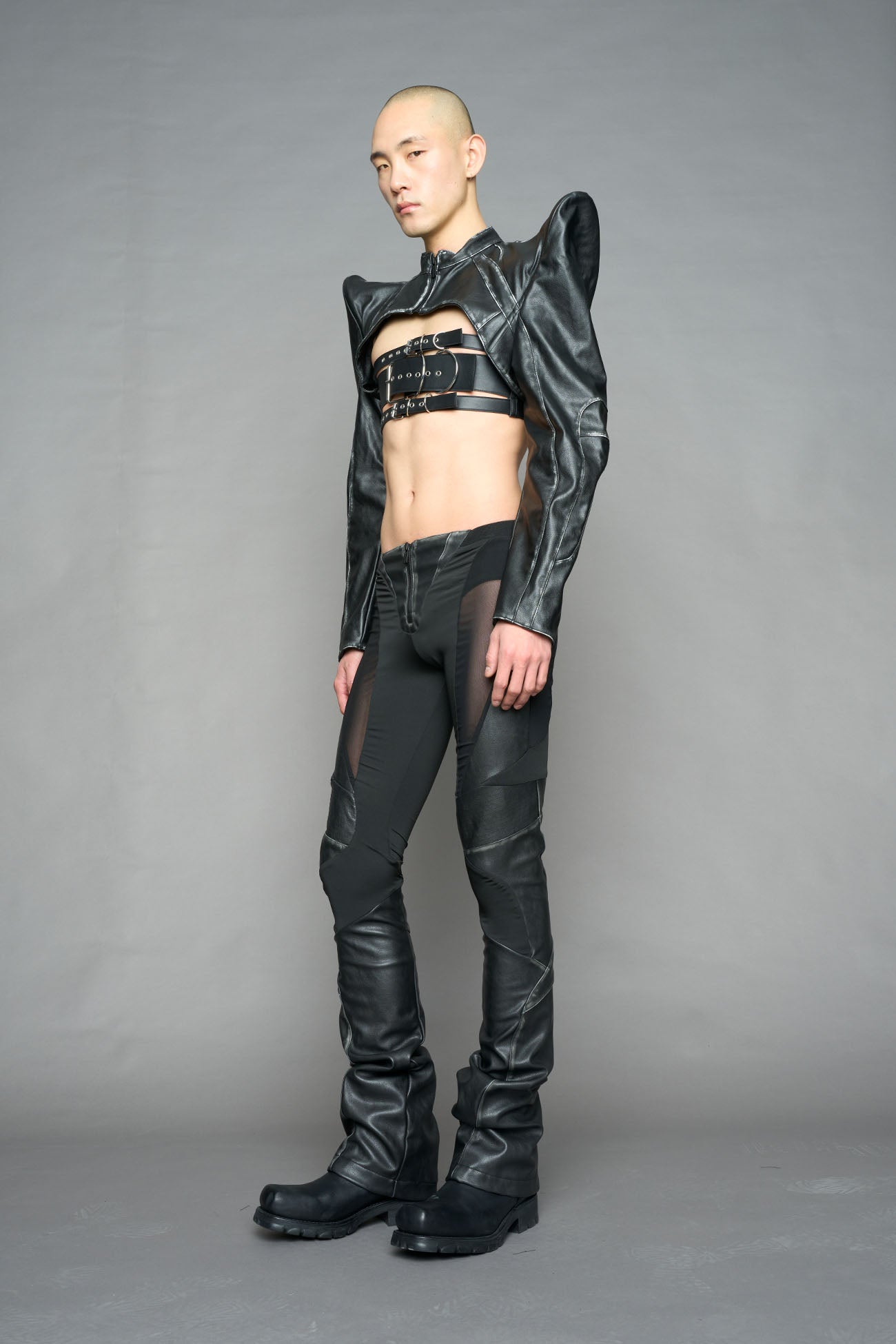 Model wearing high-waisted black washed vegan leather pants with mesh cutouts, moto-inspired paneling, and flared stacked legs – edgy streetwear trousers styled with chunky platform boots