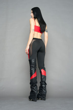 Model wearing high-waisted black red vegan leather pants with mesh cutouts, moto-inspired paneling, and flared stacked legs – edgy streetwear trousers styled with chunky platform boots
