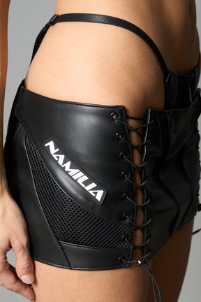 Black vegan leather moto thong mini skirt with lace-up sides, cut-out hips, and zip front – edgy Y2K streetwear skirt for clubwear or festival looks.

