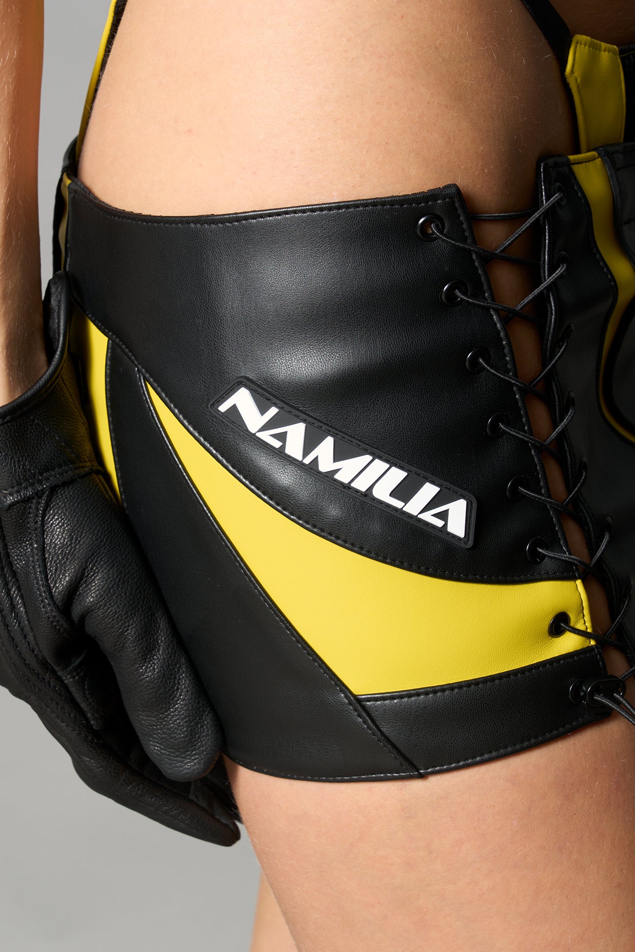 yellow vegan leather moto thong mini skirt with lace-up sides, cut-out hips, and zip front – edgy Y2K streetwear skirt for clubwear or festival looks.
