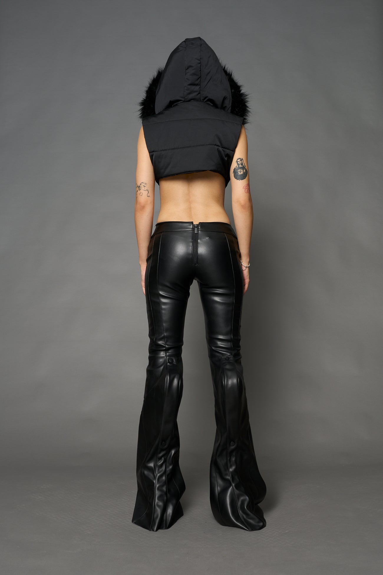 Black vegan leather stretch mutant pants with high waist, ribbed knee panels, and exaggerated flared legs by Namilia