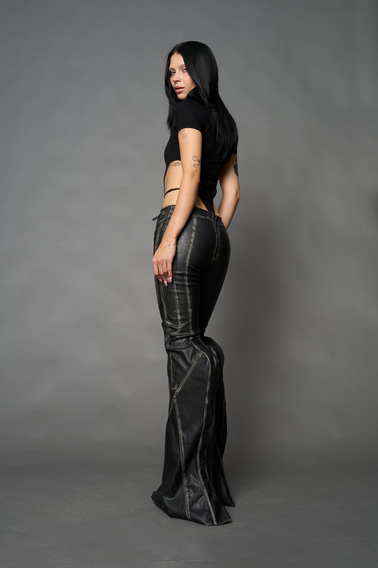 Black washed vegan leather stretch mutant pants with high waist, ribbed knee panels, and exaggerated flared legs by Namilia
