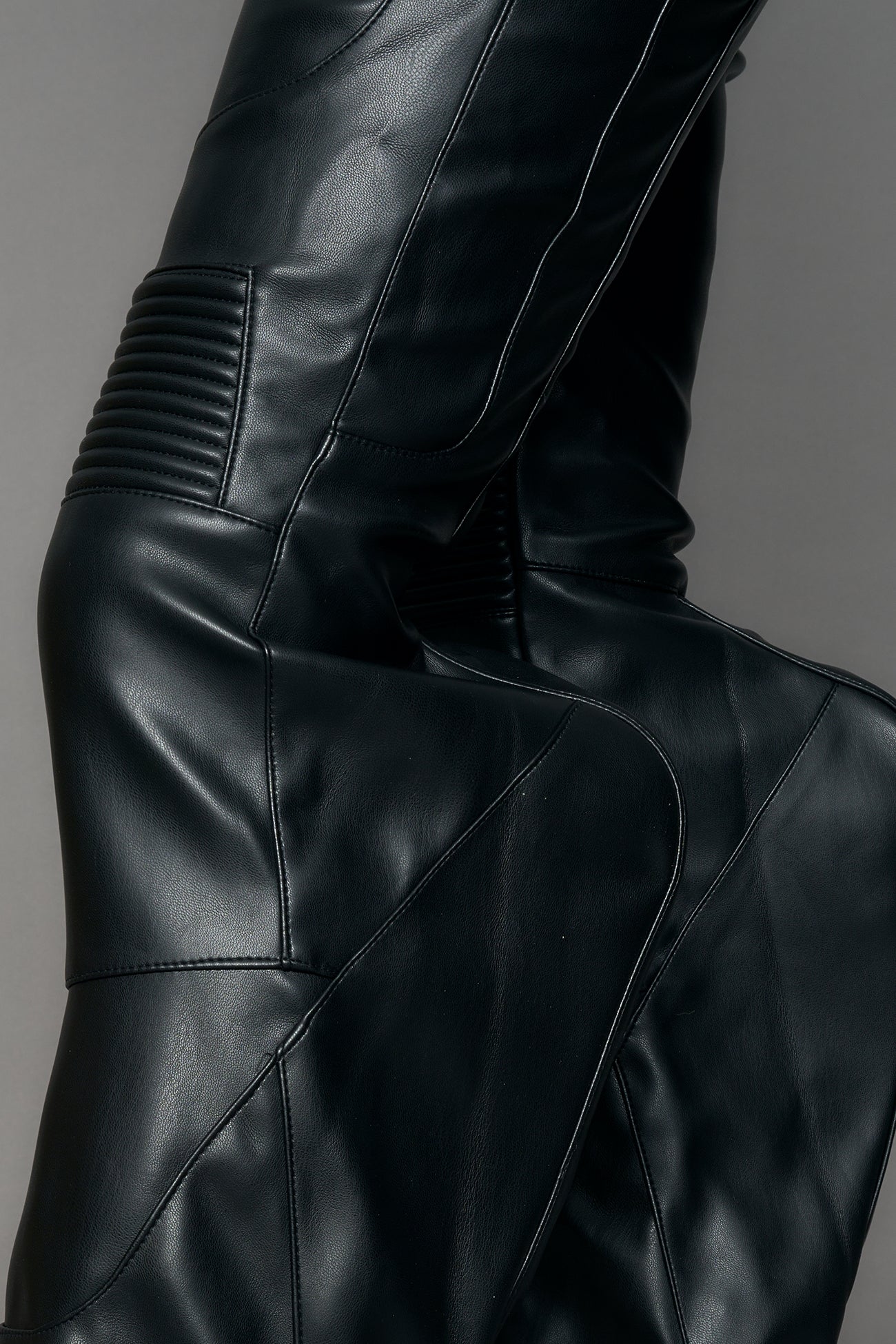Black vegan leather stretch mutant pants with high waist, ribbed knee panels, and exaggerated flared legs by Namilia