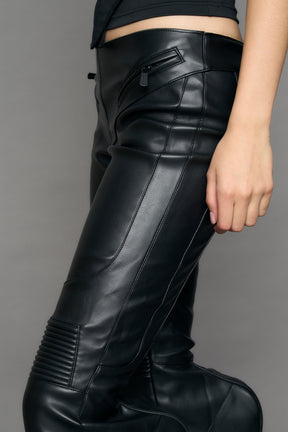 Black vegan leather stretch mutant pants with high waist, ribbed knee panels, and exaggerated flared legs by Namilia