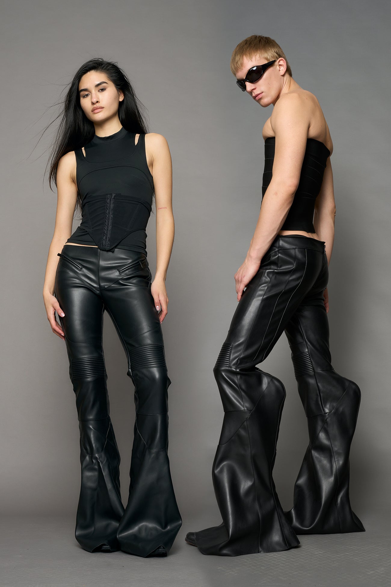 Black vegan leather stretch mutant pants with high waist, ribbed knee panels, and exaggerated flared legs by Namilia