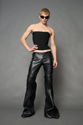 Black vegan leather stretch mutant pants with high waist, ribbed knee panels, and exaggerated flared legs by Namilia