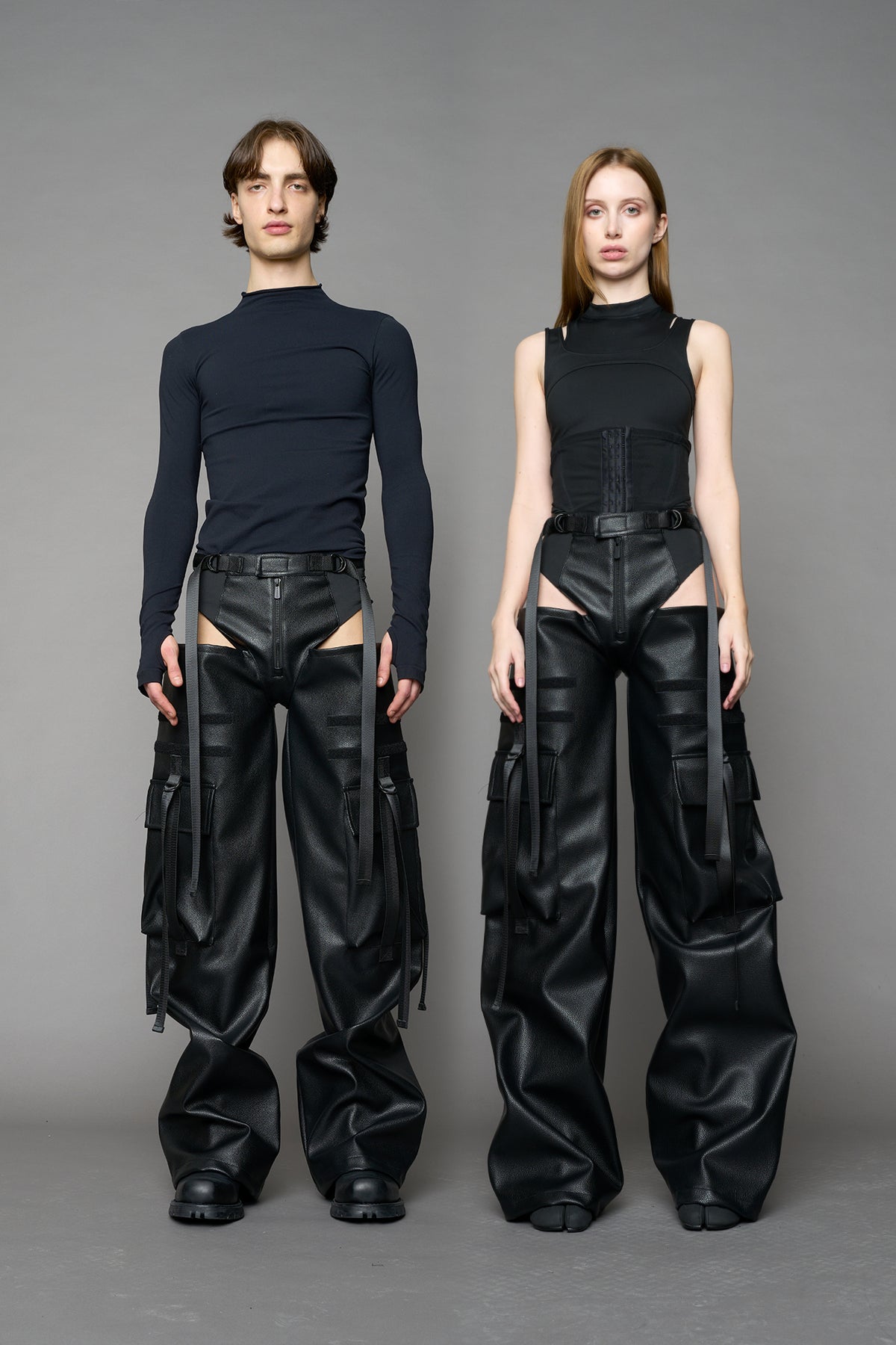 Model wearing Black vegan leather panty trousers featuring an integrated stretch panel for comfort, adjustable belt detail, and a relaxed high-waist silhouette.