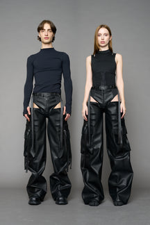 Model wearing Black vegan leather panty trousers featuring an integrated stretch panel for comfort, adjustable belt detail, and a relaxed high-waist silhouette.