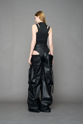 Model wearing Black vegan leather panty trousers featuring an integrated stretch panel for comfort, adjustable belt detail, and a relaxed high-waist silhouette.