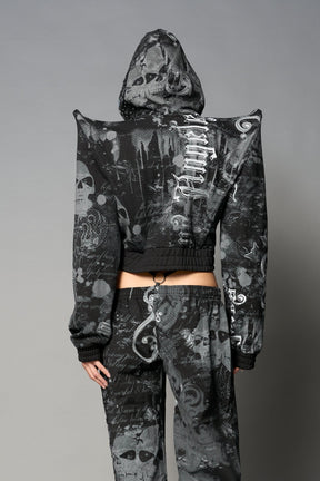 Model wearing a black print cropped hoodie with exaggerated spike shoulders, drawstring hood
