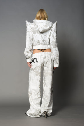 Model wearing a white print cropped hoodie with exaggerated spike shoulders, drawstring hood