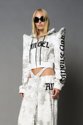 Model wearing a white print cropped hoodie with exaggerated spike shoulders, drawstring hood