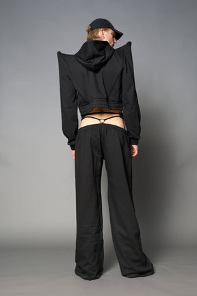 Model wearing a black cropped hoodie with exaggerated spike shoulders, drawstring hood