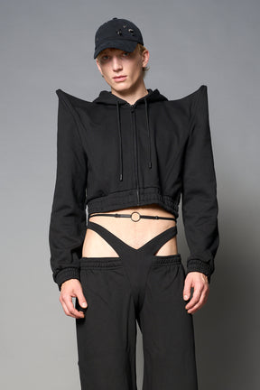 Model wearing a black cropped hoodie with exaggerated spike shoulders, drawstring hood