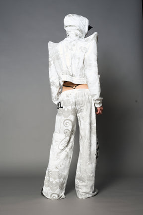Model wearing a white print cropped hoodie with exaggerated spike shoulders, drawstring hood