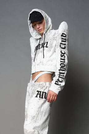 Model wearing a white print cropped hoodie with exaggerated spike shoulders, drawstring hood