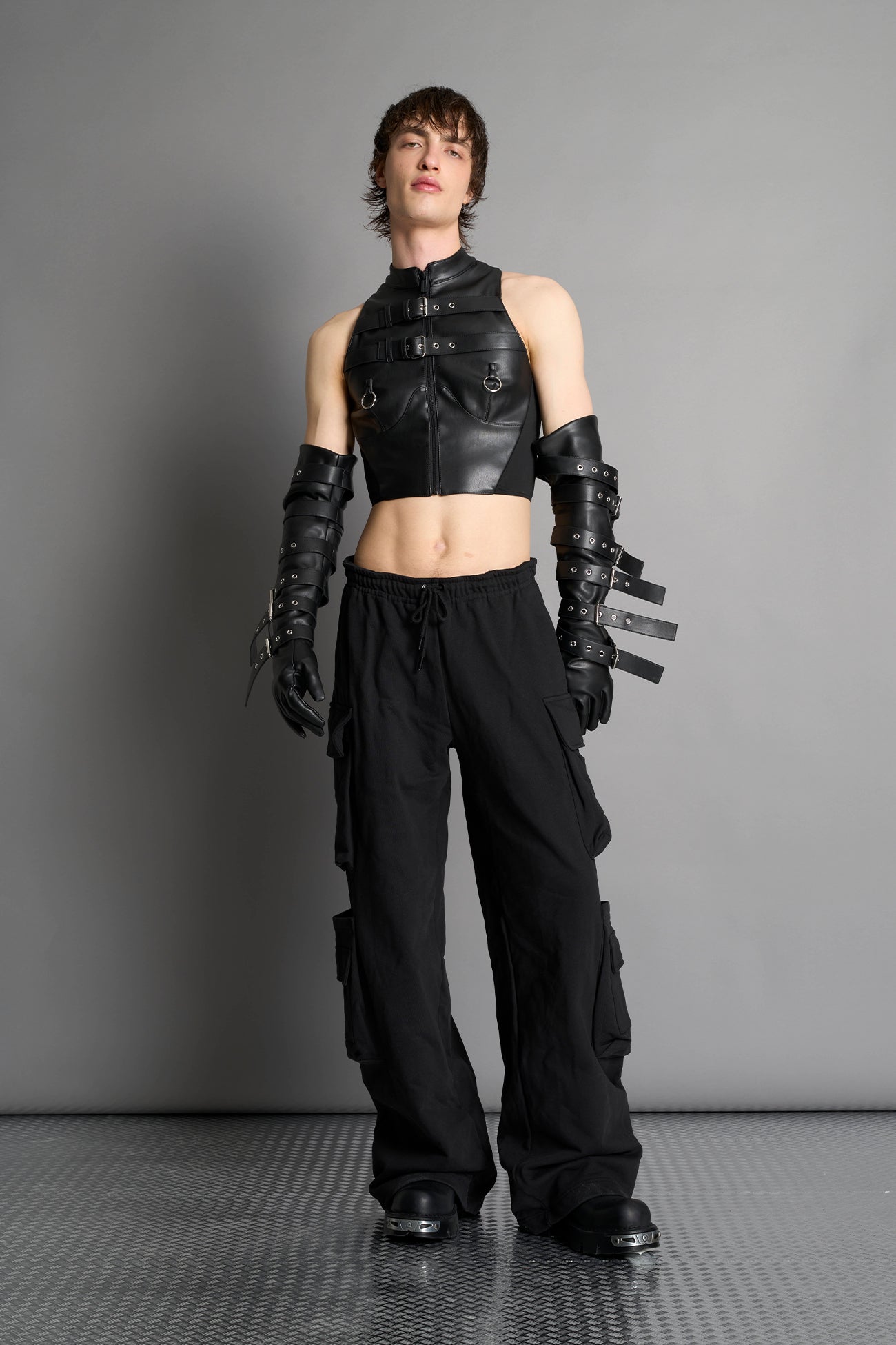 Namilia male model Piercing Top in black vegan leather featuring silver metal ring details, cutout design, and edgy Y2K-inspired crop top style. front view